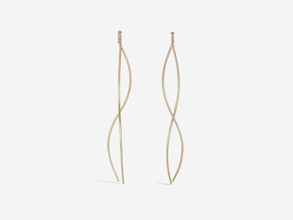 Earrings are hanging and feature two gracefully curved gold wires connected by a half inch of chain. Size is medium