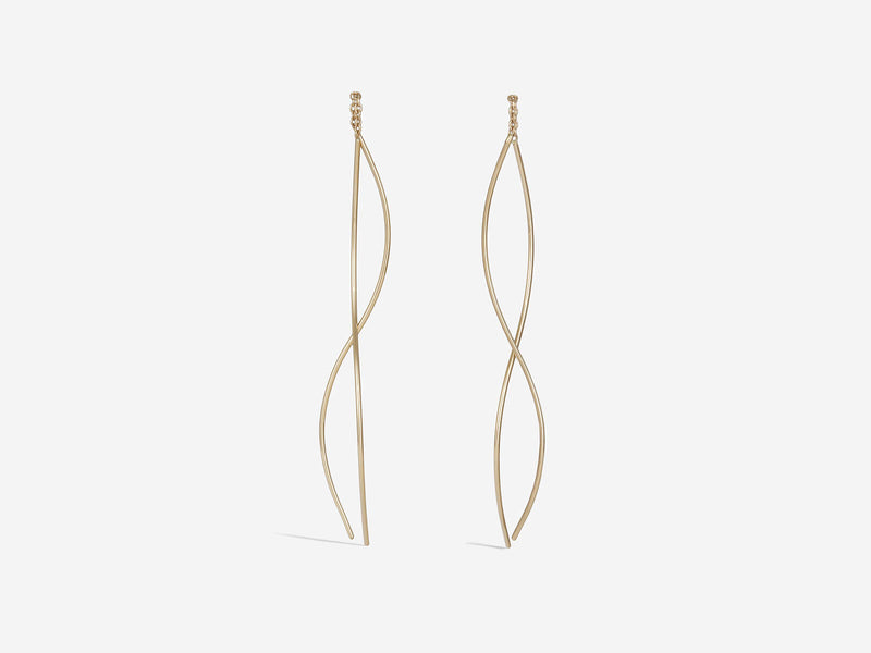 Earrings are hanging and feature two gracefully curved gold wires connected by a half inch of chain. Size is medium