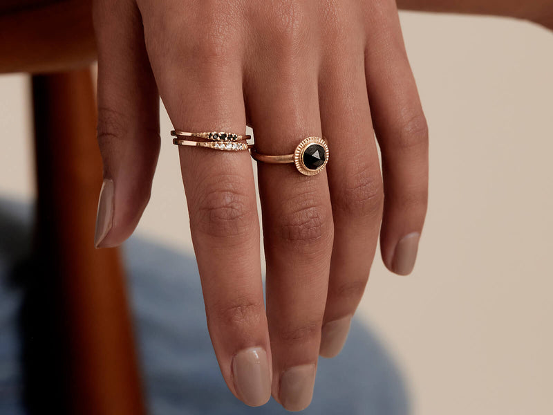 Model wears a Black and White Diamond Flamenco Stack Rings together on her pointer finger, next to the Limited Edition Rose-Cut Black Diamond Burst Ring on her middle finger.. 