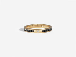 A channel set eternity band is almost complete excluding a small section of gold in front that has a single flush set white diamond in the middle