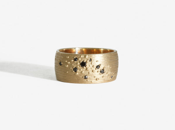 Front view showing a diagonal constellation-like group of raised gold beads acting as prongs for variously sized black diamonds