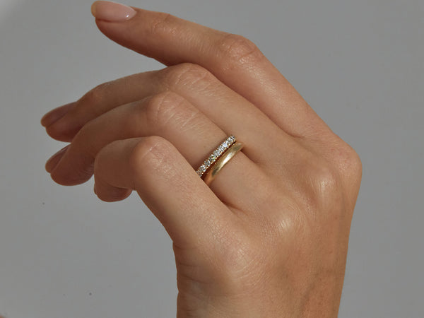 close up of model's hand wearing 2 mm eternity band and medium organic rounded band