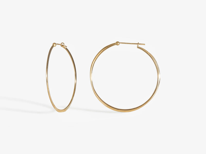 A combined profile and three-quarters view. Earrings close with simple latch and are forged to create an organic wave-like shape.