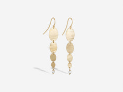 Four gold hammered ovals graduating in size from large to small hang freely on an earwire. At the bottom of the smallest oval is a two millimeter diamond sitting in a diamond shaped setting with open sides. 