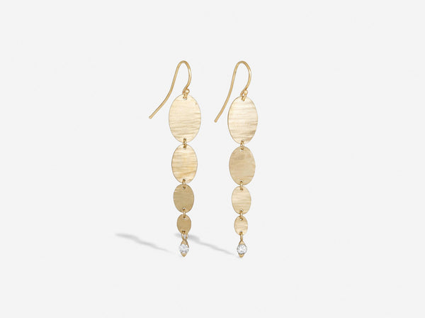 Four gold hammered ovals graduating in size from large to small hang freely on an earwire. At the bottom of the smallest oval is a two millimeter diamond sitting in a diamond shaped setting with open sides. 