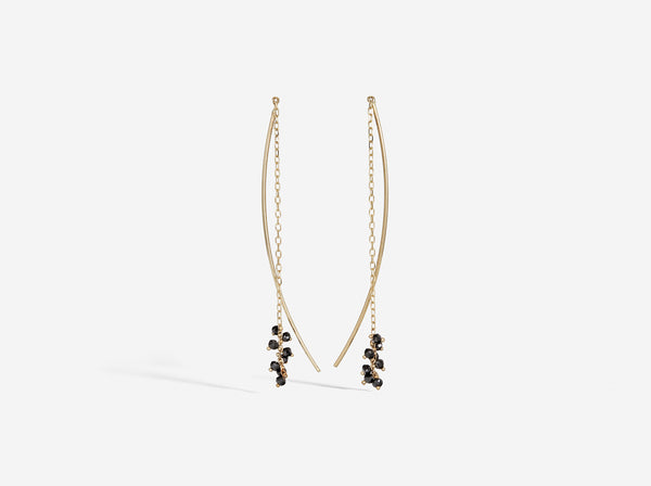 Chain adorned with black diamond rondelles is attached to a curved segment of gold wire to create an earring