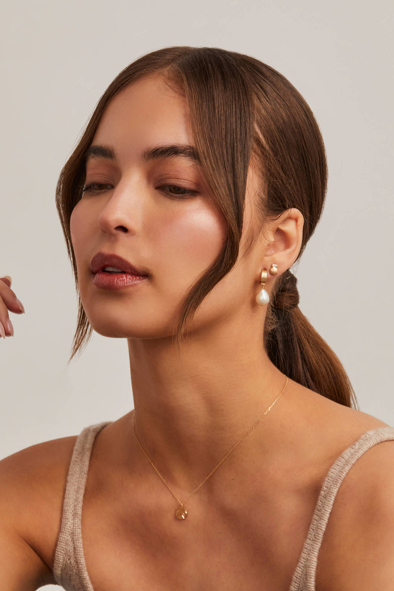 model wears small round stud with baguette diamond