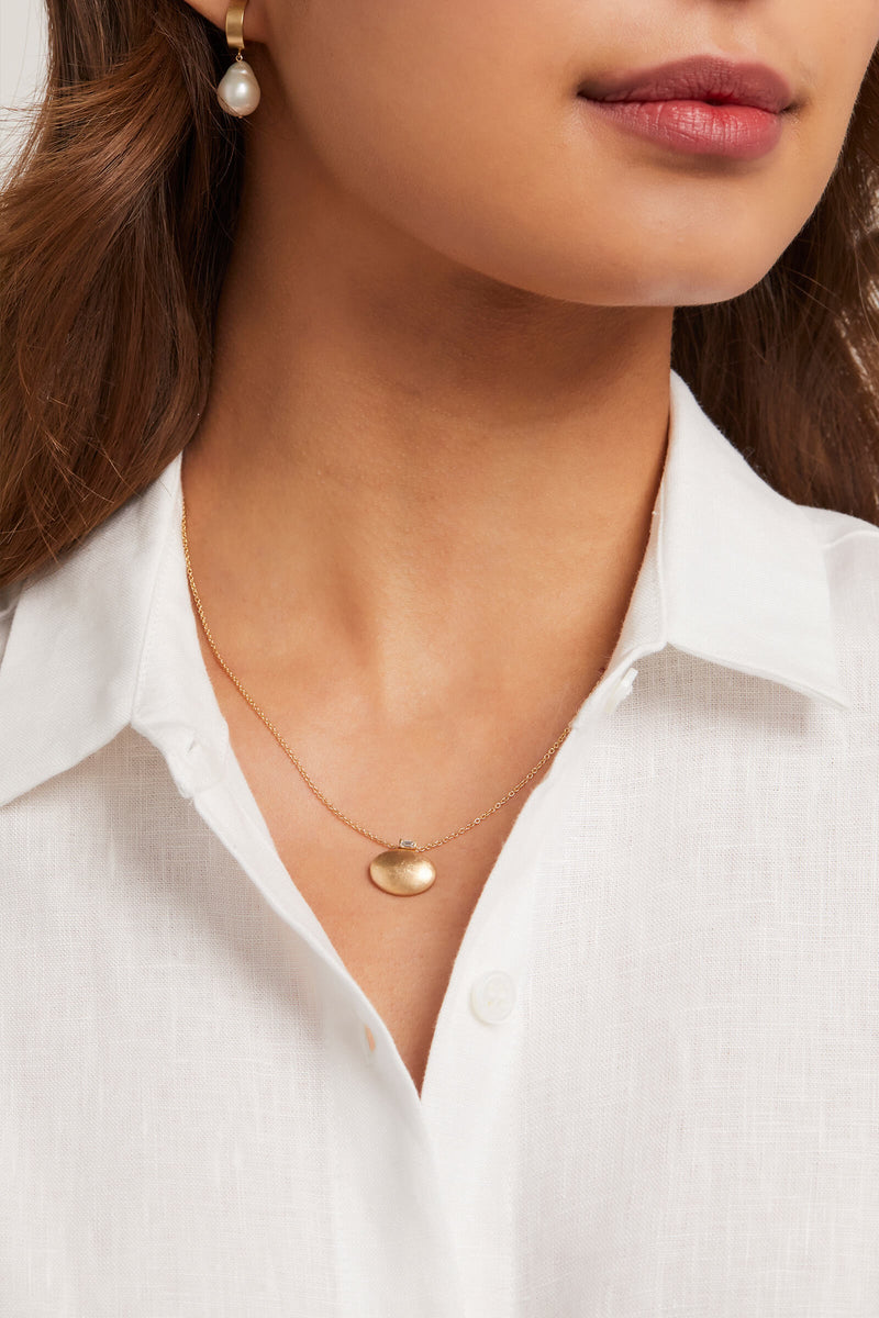 model wears large oval pendant with diamond baguette accent 