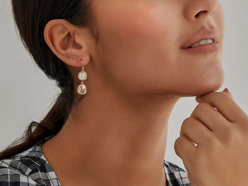 Close up of model waring double diamond slice drop earrings
